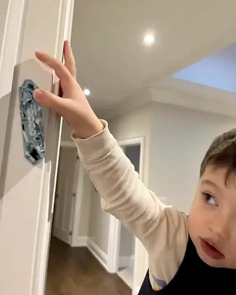 A child reaching up to touch a POPPSI mezuzah on a doorpost